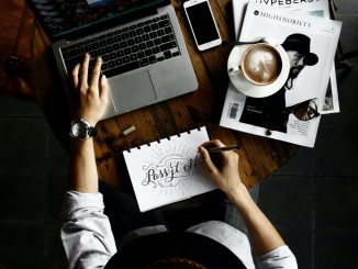 person sitting facing laptop computer with sketch pad